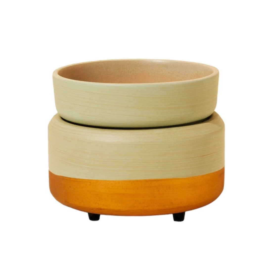 Photo of our Sage Wax Warmer. It is circular in shape with a removable round dish sitting on top. It has tiny brown feet on the bottom and is a sage green in colour with a gold stripe on the bottom.