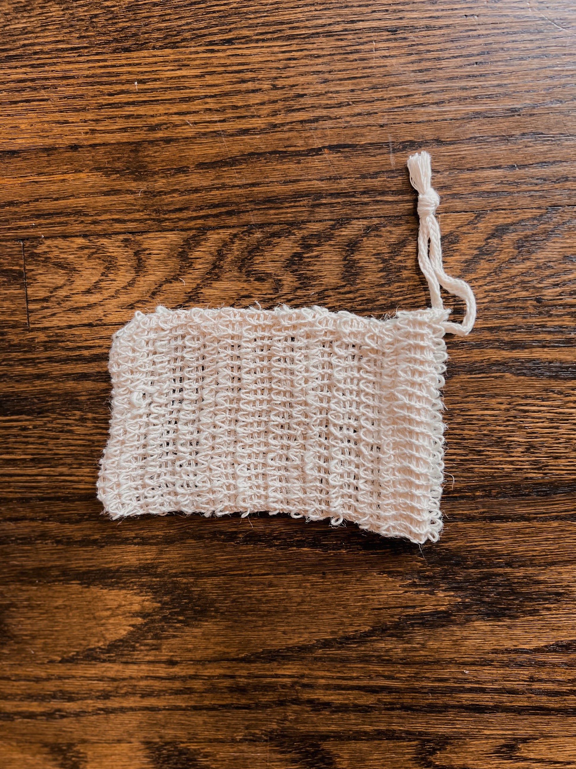 A photo of our sisal soap bag. The material is made of beige, natural fibres woven together to help gently exfoliate the skin. There is a drawstring on top. It is approximately 5” long.